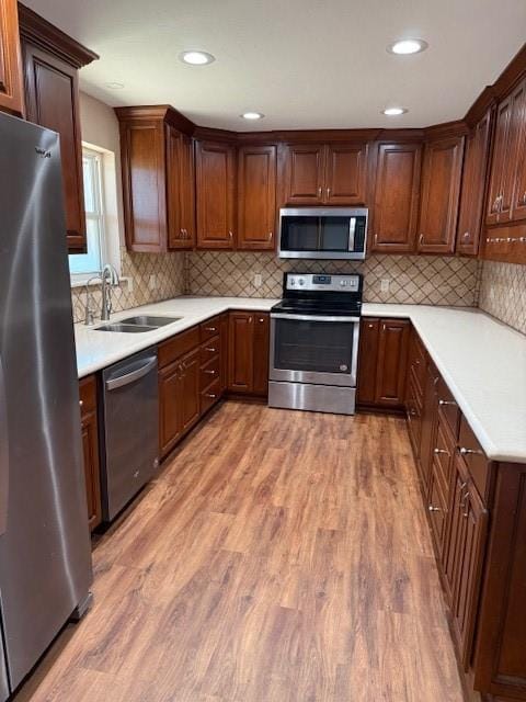 kitchen featuring appliances with stainless steel finishes, tasteful backsplash, sink, and wood-type flooring