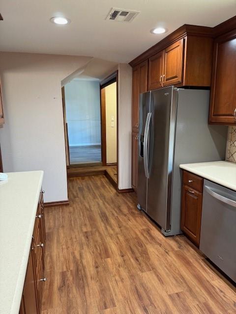 kitchen with stainless steel appliances, hardwood / wood-style flooring, and decorative backsplash