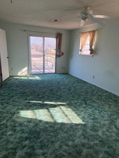 empty room featuring dark carpet, a textured ceiling, and ceiling fan