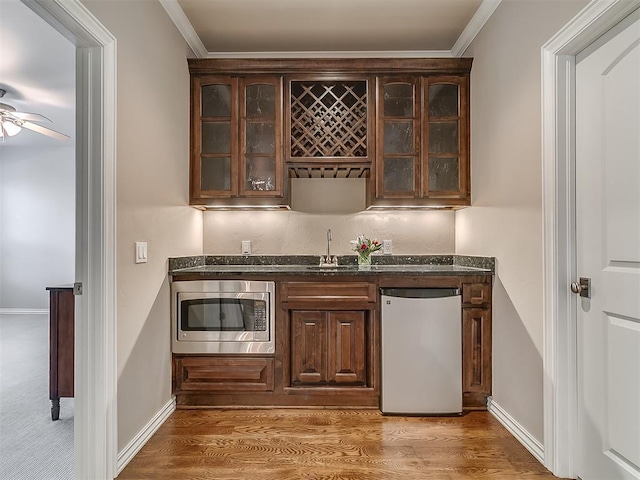 bar with fridge, stainless steel microwave, crown molding, and sink