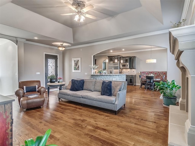 living room featuring a raised ceiling, crown molding, ceiling fan, and dark hardwood / wood-style flooring