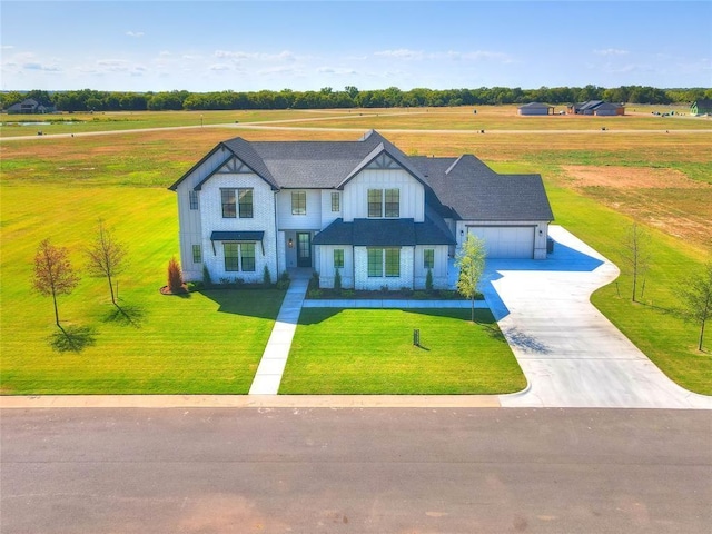 view of front of house with a rural view, a front yard, and a garage