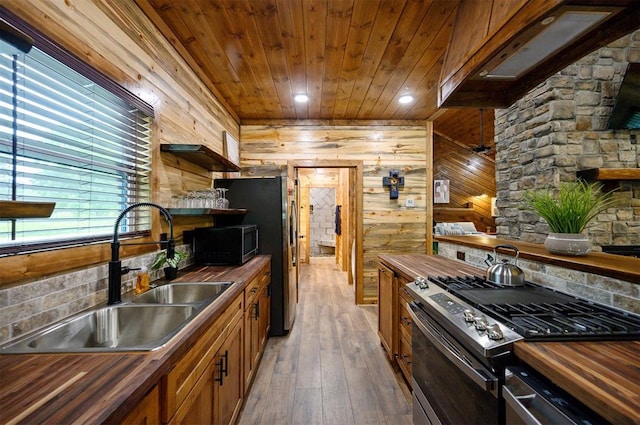 kitchen with sink, stainless steel appliances, wooden walls, butcher block counters, and dark hardwood / wood-style flooring