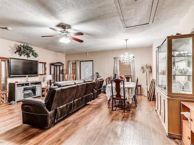 living room with light hardwood / wood-style floors, a textured ceiling, and ceiling fan with notable chandelier