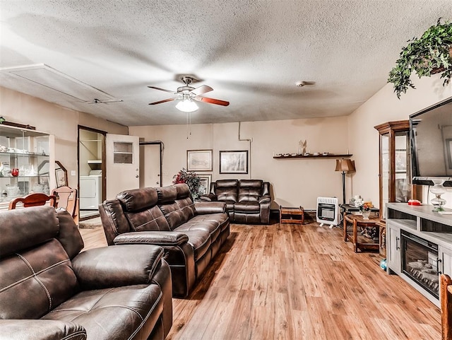 living room featuring washer / dryer, a textured ceiling, light hardwood / wood-style floors, and heating unit