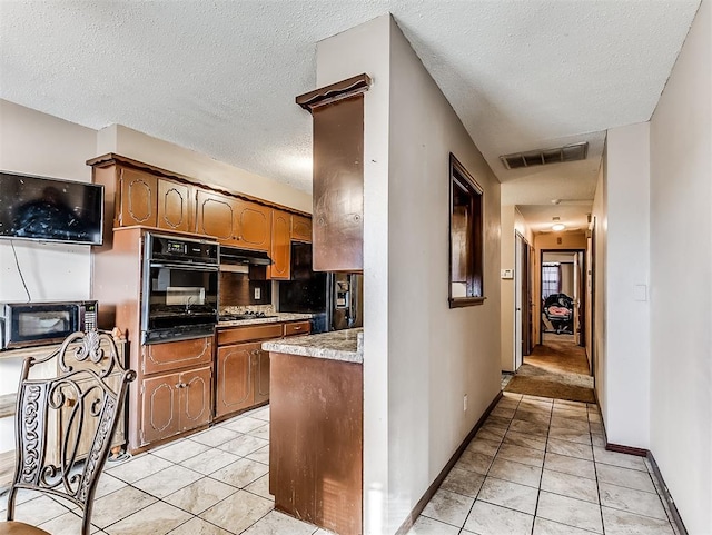 kitchen with decorative backsplash, a textured ceiling, light tile patterned floors, and black appliances