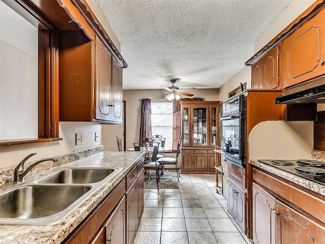 kitchen featuring ceiling fan, oven, cooktop, sink, and a textured ceiling