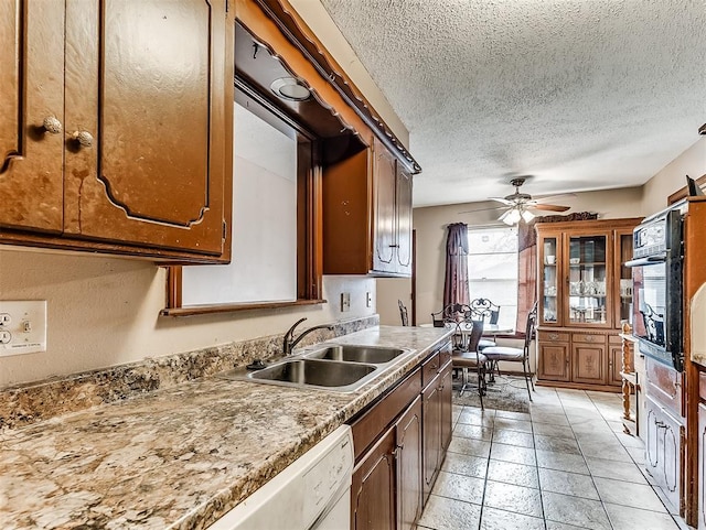 kitchen with a textured ceiling, white dishwasher, sink, oven, and ceiling fan