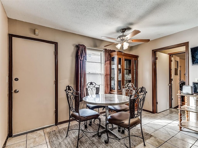 tiled dining space with ceiling fan and a textured ceiling