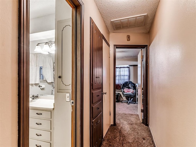 hallway with carpet floors and a textured ceiling