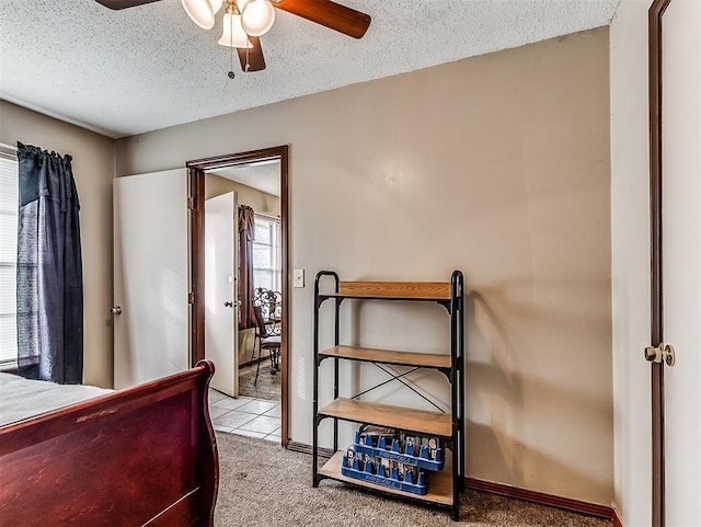 bedroom featuring ceiling fan, light colored carpet, and a textured ceiling