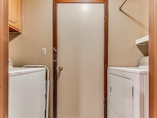 clothes washing area featuring washer and clothes dryer and cabinets