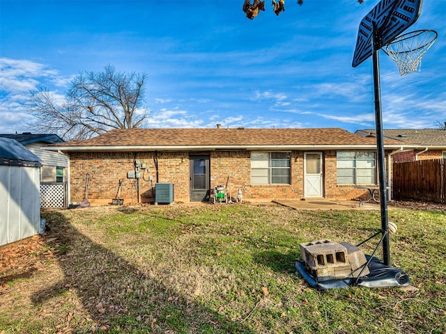 back of house with a lawn, a fire pit, and central air condition unit