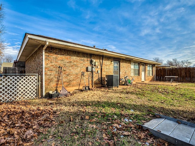 back of property featuring central AC unit and a lawn