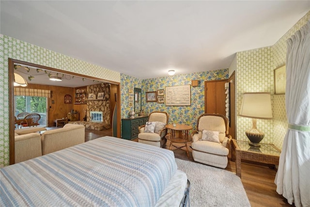 bedroom with hardwood / wood-style flooring and a stone fireplace