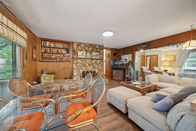 living room with wooden walls, plenty of natural light, built in shelves, and a fireplace