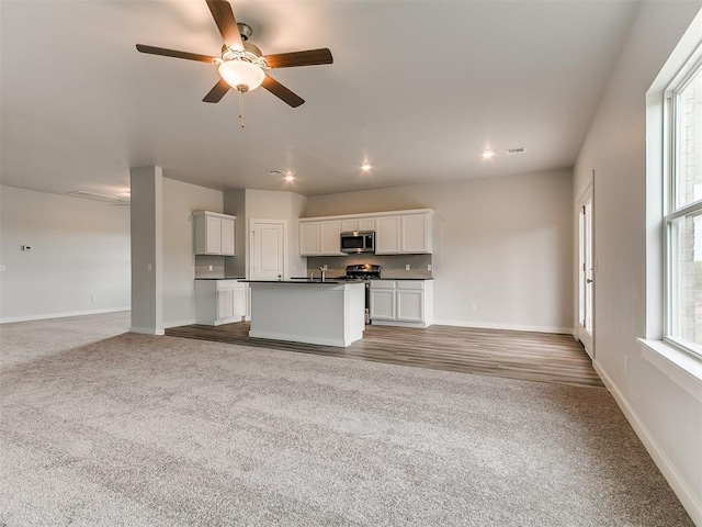 13156 Mannington Rd, Edmond, OK 73025 - kitchen featuring stainless steel appliances, open floor plan, dark countertops, carpet flooring, and a ceiling fan