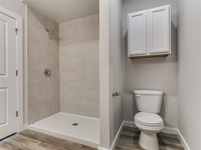 13156 Mannington Rd, Edmond, OK 73025 - bathroom with wood finished floors, toilet, tiled shower, and baseboards