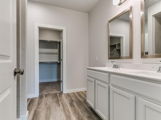 13156 Mannington Rd, Edmond, OK 73025 - bathroom featuring double vanity, wood finished floors, a walk in closet, and baseboards