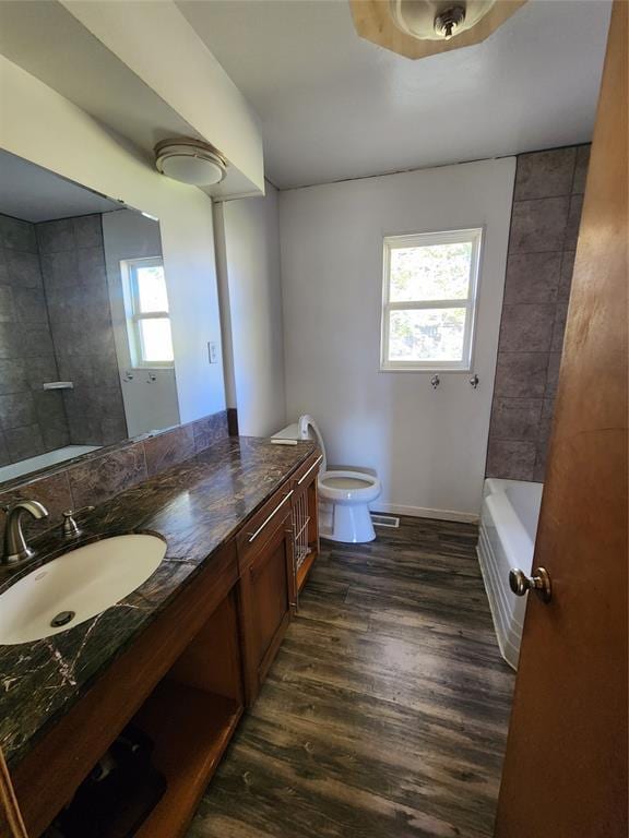 bathroom with a tub to relax in, vanity, plenty of natural light, and hardwood / wood-style flooring