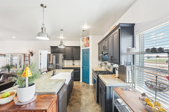 kitchen with sink, a kitchen island with sink, pendant lighting, and stainless steel appliances