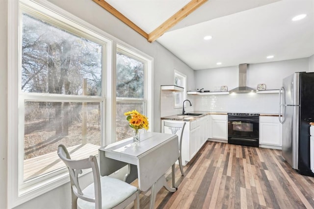 kitchen with white cabinets, electric range, wall chimney range hood, decorative backsplash, and stainless steel refrigerator