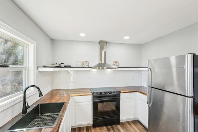 kitchen with stainless steel fridge, sink, electric range, wall chimney range hood, and wood counters