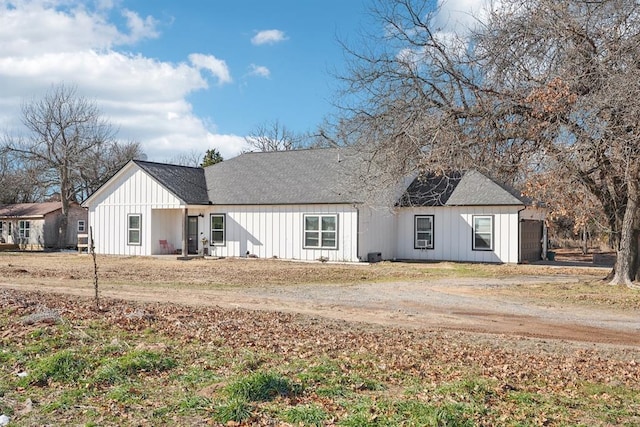 modern farmhouse style home with dirt driveway, roof with shingles, and board and batten siding