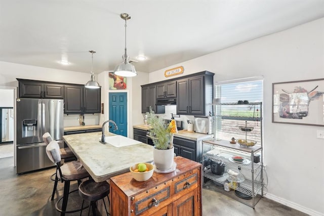 kitchen featuring concrete flooring, light countertops, a sink, and stainless steel fridge with ice dispenser