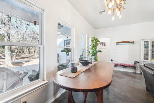 dining space with concrete flooring, visible vents, and a notable chandelier