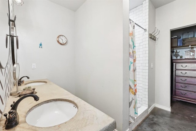 full bath featuring a stall shower, double vanity, a sink, and concrete floors