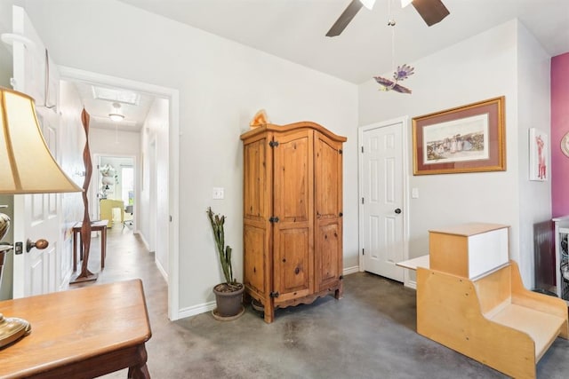 interior space with attic access, ceiling fan, and baseboards