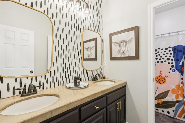 full bath with double vanity, wallpapered walls, and a sink