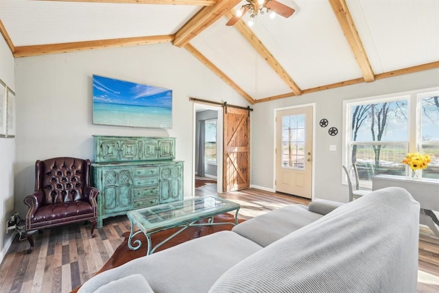 living area featuring lofted ceiling with beams, a barn door, and wood finished floors