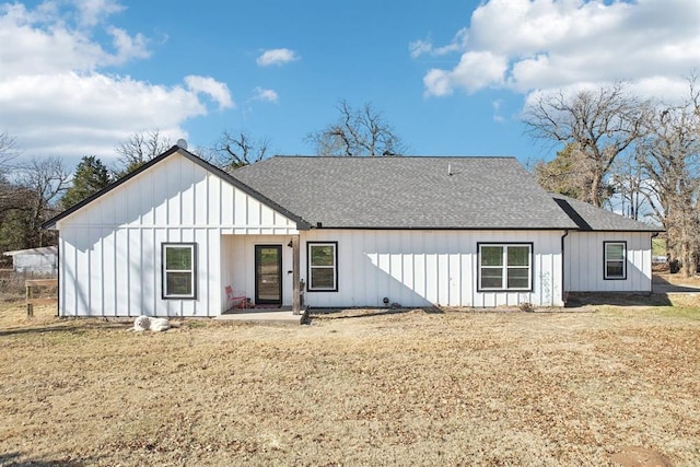 view of front of house featuring board and batten siding, roof with shingles, and a front lawn