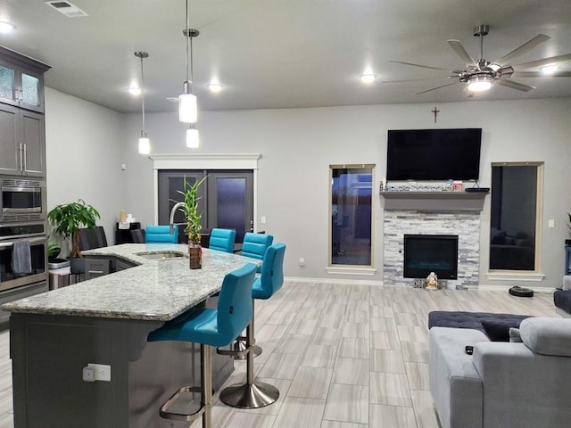 kitchen with a center island with sink, pendant lighting, sink, a kitchen breakfast bar, and stainless steel appliances