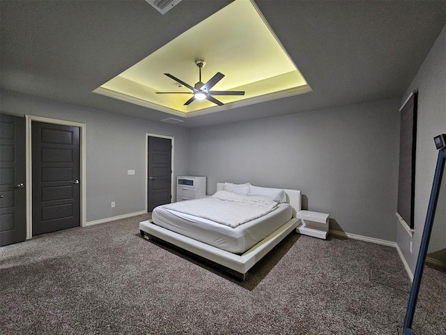 carpeted bedroom featuring ceiling fan and a tray ceiling