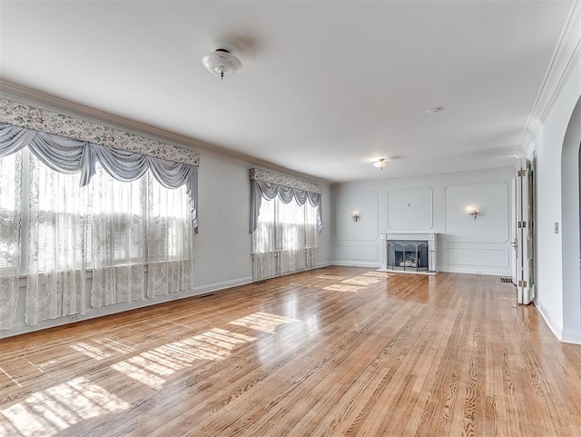 unfurnished living room with crown molding and light hardwood / wood-style flooring