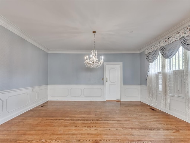 unfurnished dining area with a notable chandelier, light hardwood / wood-style floors, and crown molding