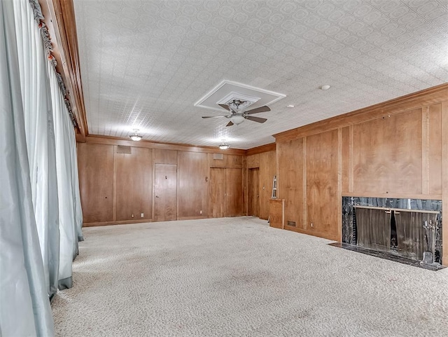 carpeted spare room featuring wood walls and ceiling fan