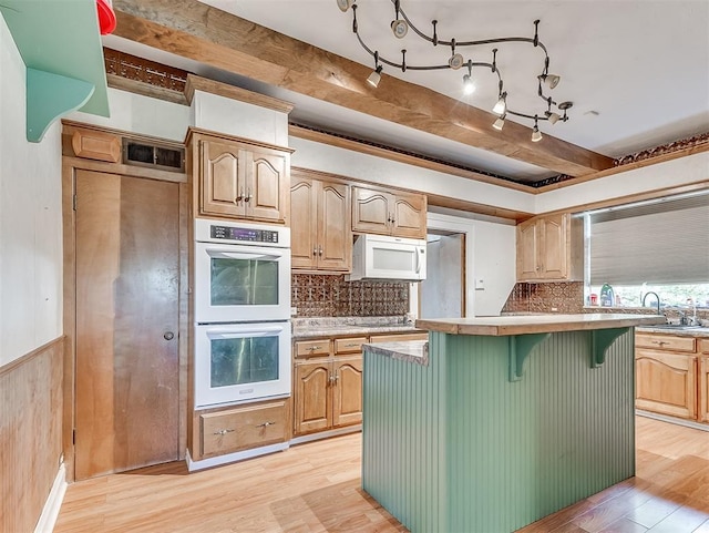 kitchen with a center island, double wall oven, a kitchen breakfast bar, light hardwood / wood-style flooring, and black electric cooktop