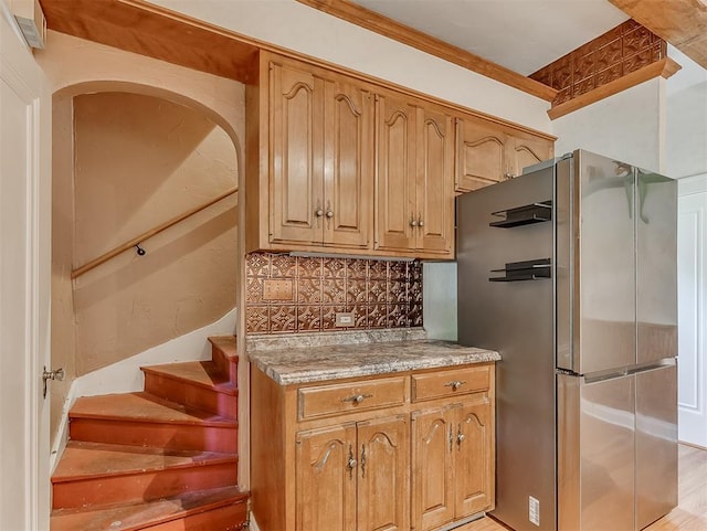 kitchen with light hardwood / wood-style floors, stainless steel fridge, crown molding, and tasteful backsplash