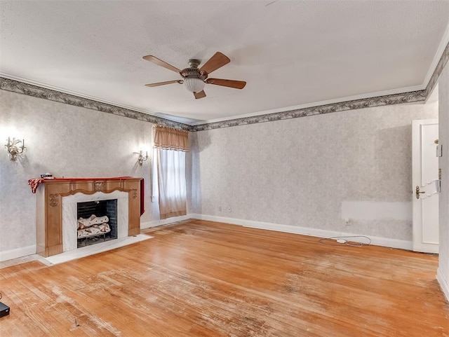 unfurnished living room with a high end fireplace, hardwood / wood-style floors, ceiling fan, and ornamental molding