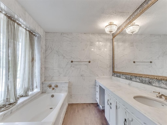 bathroom featuring vanity, a textured ceiling, hardwood / wood-style floors, and a bath