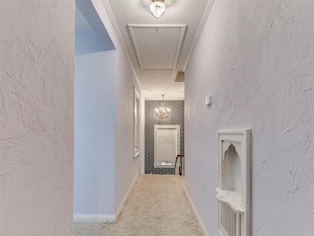 hallway with a chandelier, ornamental molding, and carpet