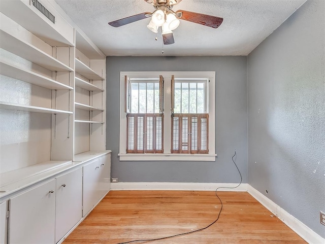 interior space with a textured ceiling, ceiling fan, and light hardwood / wood-style floors