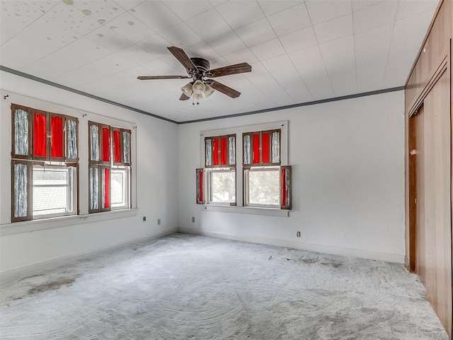 carpeted spare room with ceiling fan and crown molding