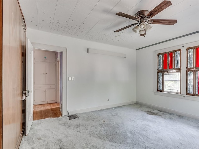 empty room with ceiling fan and light carpet