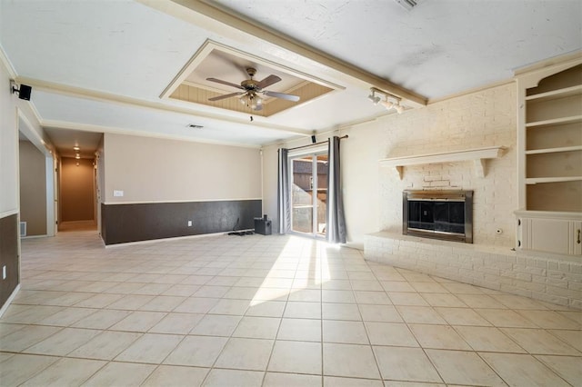 unfurnished living room featuring built in shelves, light tile patterned flooring, ceiling fan, and a fireplace