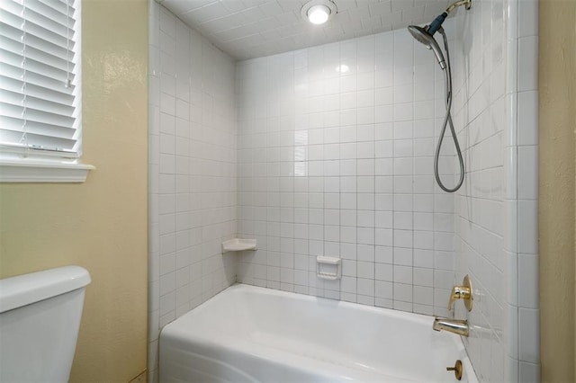 bathroom featuring toilet and tiled shower / bath